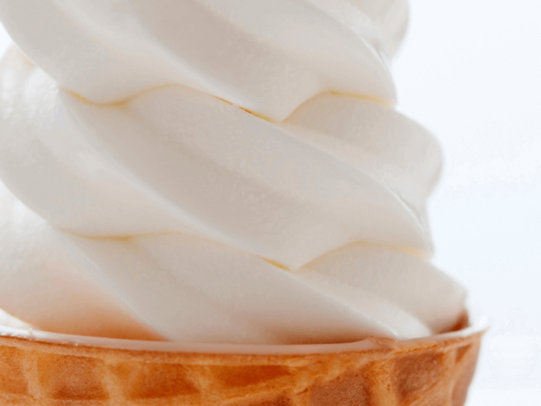 close up of vanilla soft serve in a waffle cone